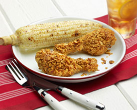 Two crispy oven-fried chicken drumsticks and corn on the cob on a plate