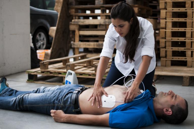 Woman using a defibrillator on a man lying on the ground